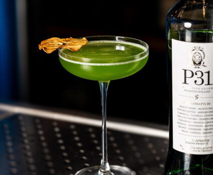 Cocktail Trentunesimo Elis servito in coppetta, realizzato con P31 Aperitivo Green, mela e distillato di pala di fico siciliano, decorato con fettina essiccata. Una ricetta semplice e fresca.