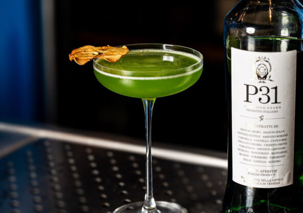 Cocktail Trentunesimo Elis servito in coppetta, realizzato con P31 Aperitivo Green, mela e distillato di pala di fico siciliano, decorato con fettina essiccata. Una ricetta semplice e fresca.