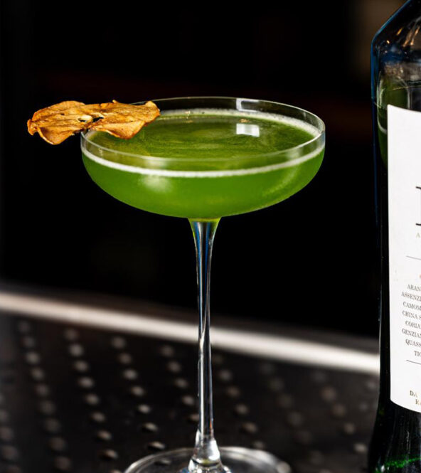 Cocktail Trentunesimo Elis servito in coppetta, realizzato con P31 Aperitivo Green, mela e distillato di pala di fico siciliano, decorato con fettina essiccata. Una ricetta semplice e fresca.