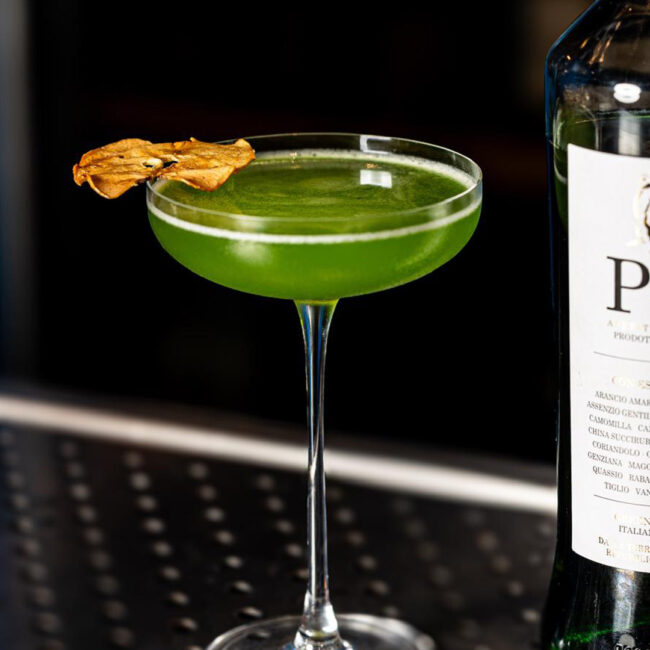 Cocktail Trentunesimo Elis servito in coppetta, realizzato con P31 Aperitivo Green, mela e distillato di pala di fico siciliano, decorato con fettina essiccata. Una ricetta semplice e fresca.